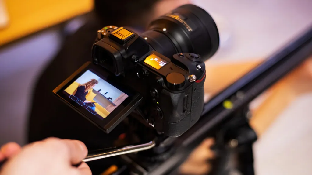 Camera on a tripod shooting a student with tablet on sofa.