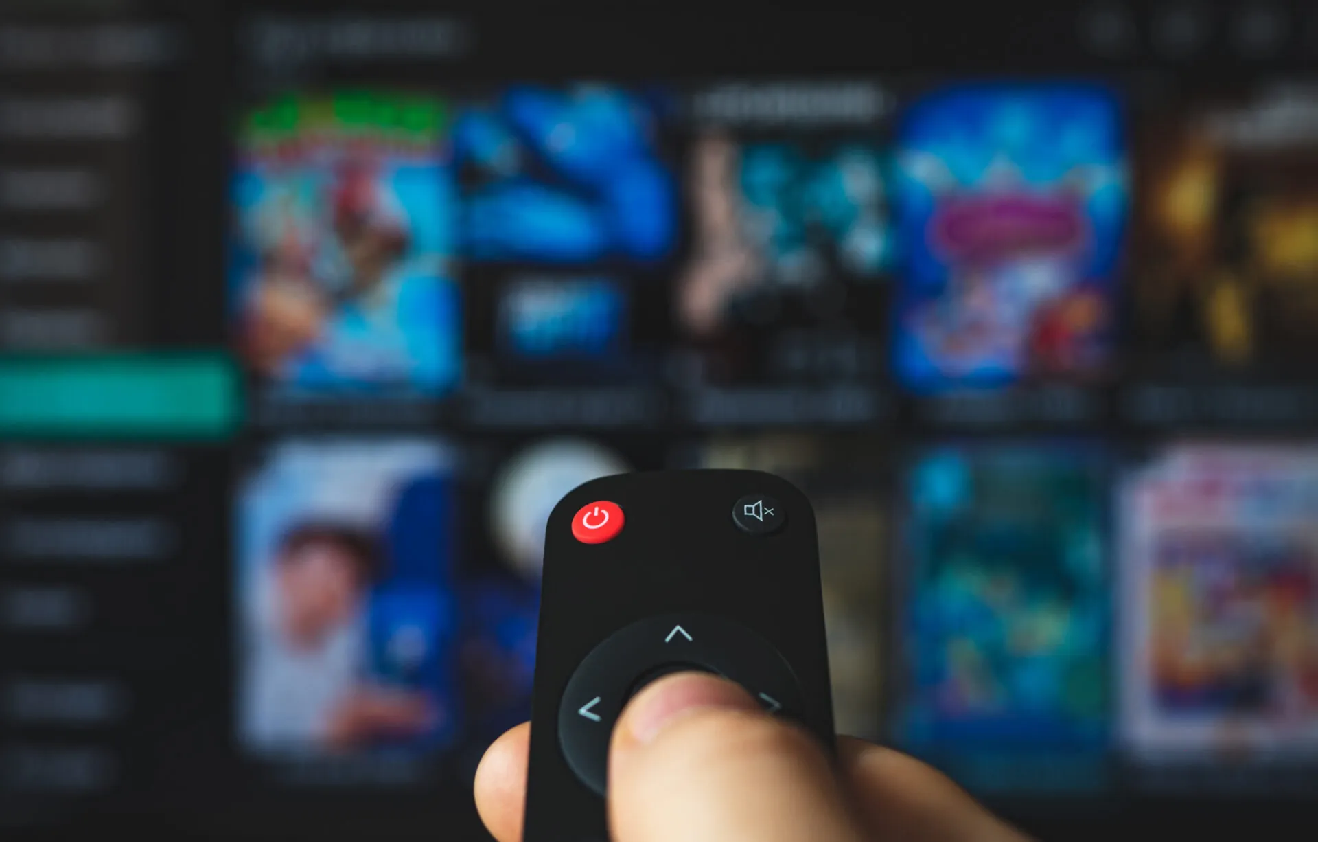 Male hand with remote control pointing on Smart TV.