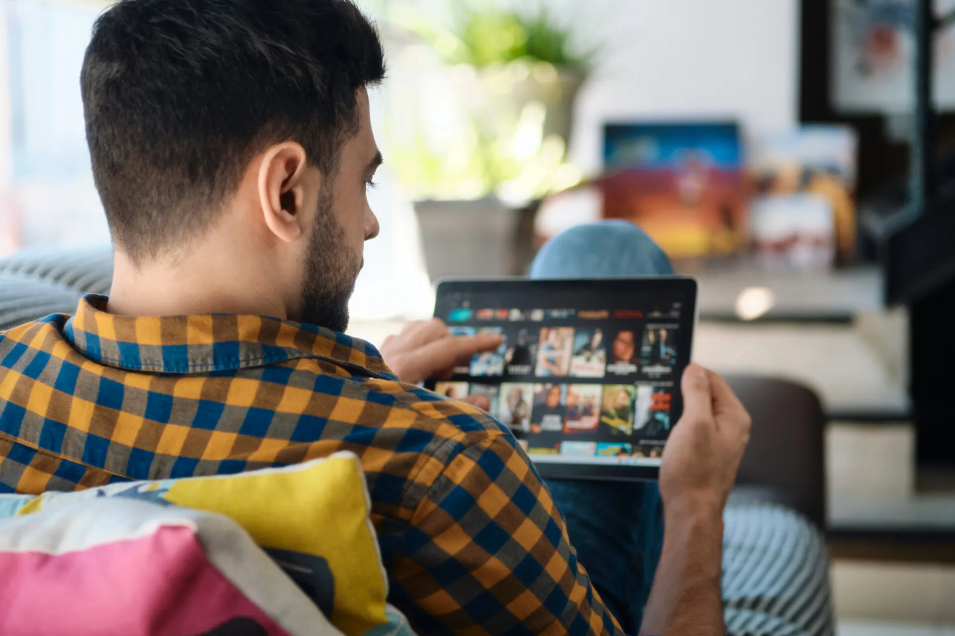 Man streaming content on a tablet at home, representing the OTT experience in the context of OTT vs CTV.