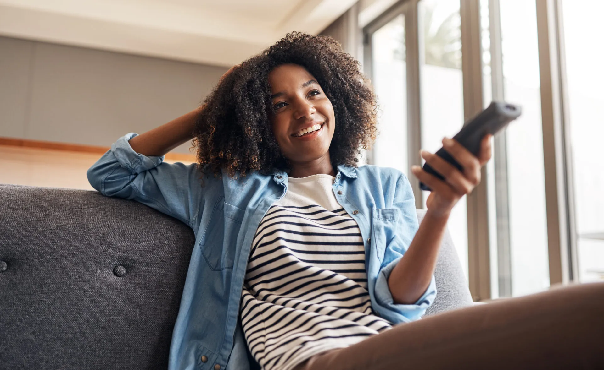 Young woman streaming content on connected TV while sitting on a couch