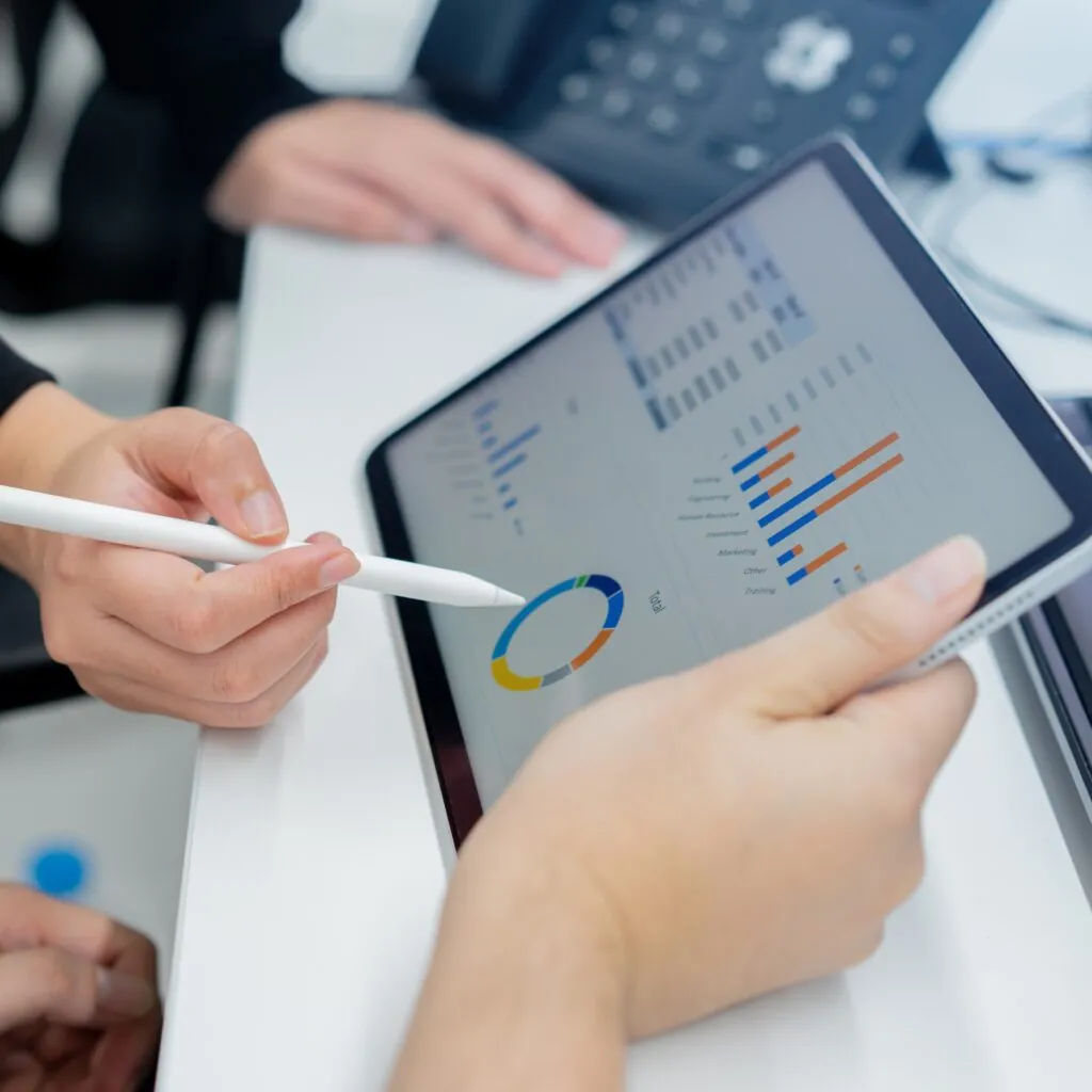 Marketers analyzing CTV campaign attribution data on a tablet showing charts and performance metrics.