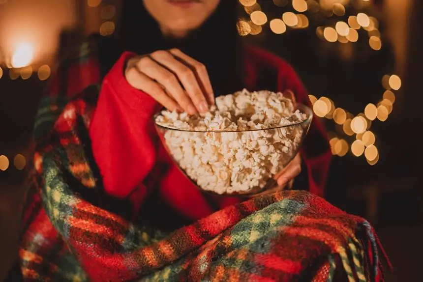 Student eating popcorn while watching streaming TV during the holidays.